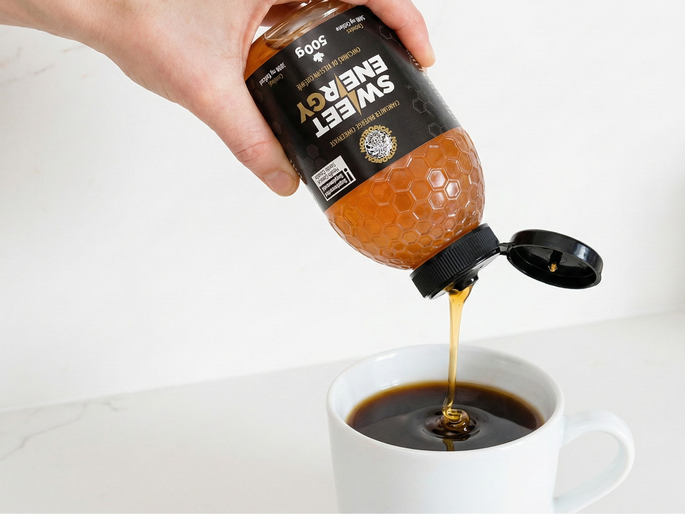 Hand pouring sweetener from a bottle into a cup of coffee on a white background. Nootropical SWEETENERGY